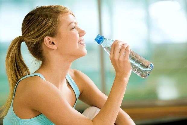 Женщина пьет воду из бутылки