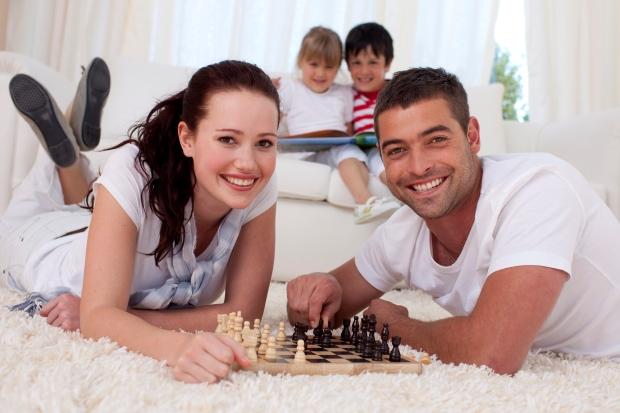 супруги играют в шахматы на полу