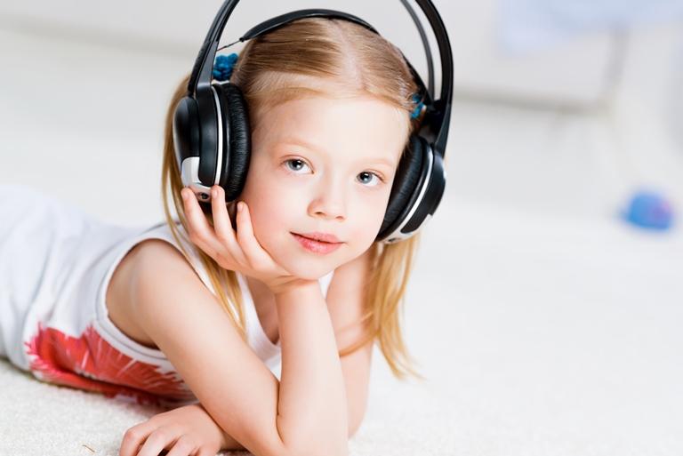 маленькая девочка слышает музыку в наушниках