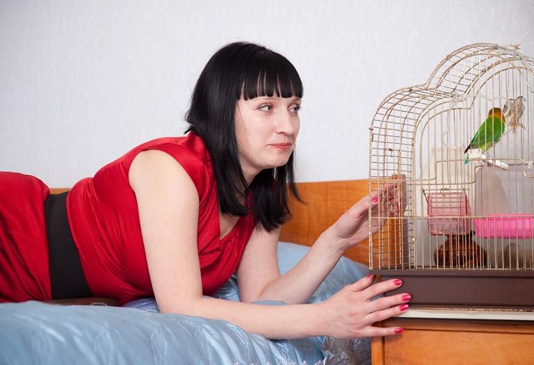 женщина возле клетки с попугаем