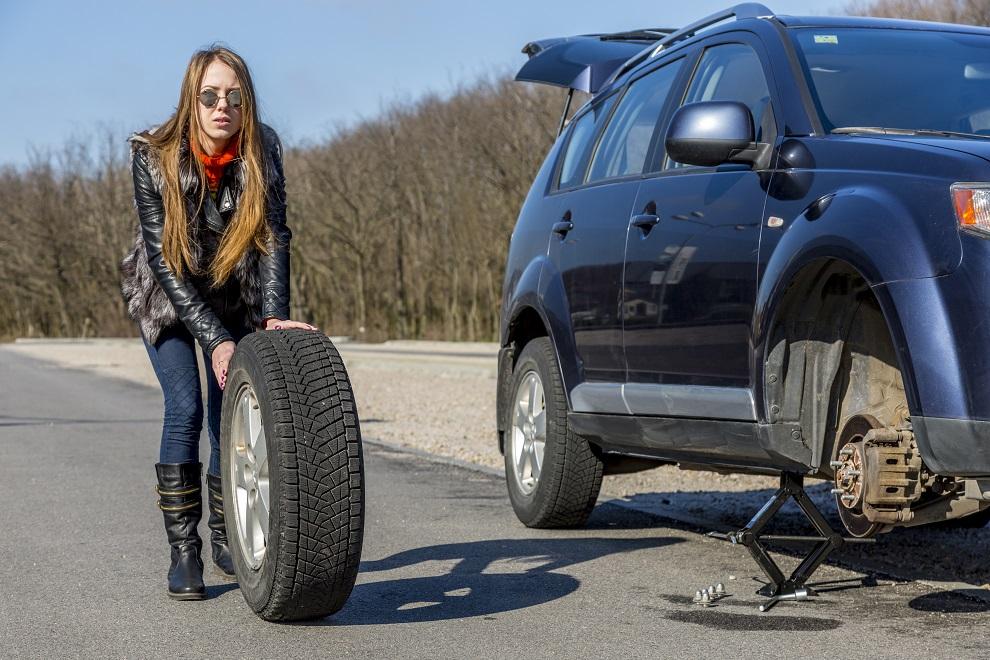 Женщина меняет колесо автомобиля