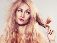 : Young woman looking at split ends. Damaged long hair