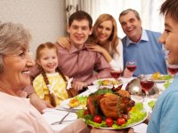 pressmaster: Portrait of happy grandmother holding tray with roasted turkey and looking at her grandson