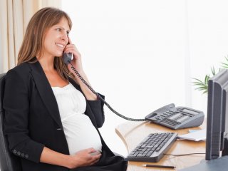 беременная женщина разговаривает по телефону в офисе