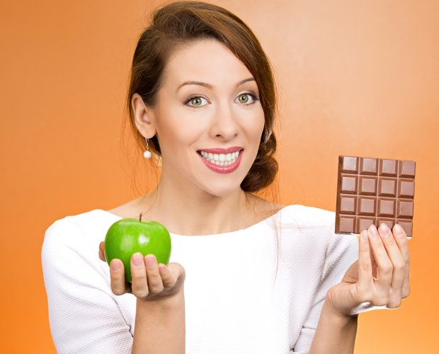 женщина держит шоколадку и яблоко