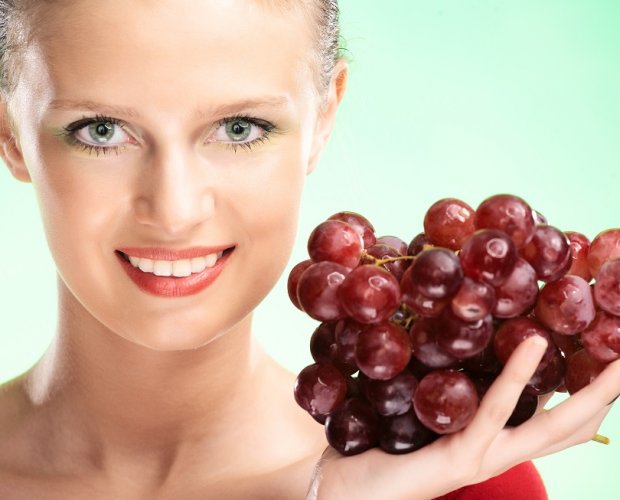 Женщина держит ветку винограда