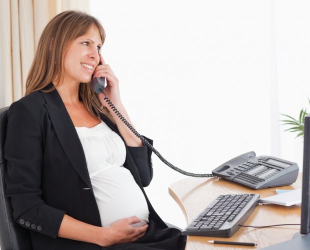 беременная женщина разговаривает по телефону в офисе