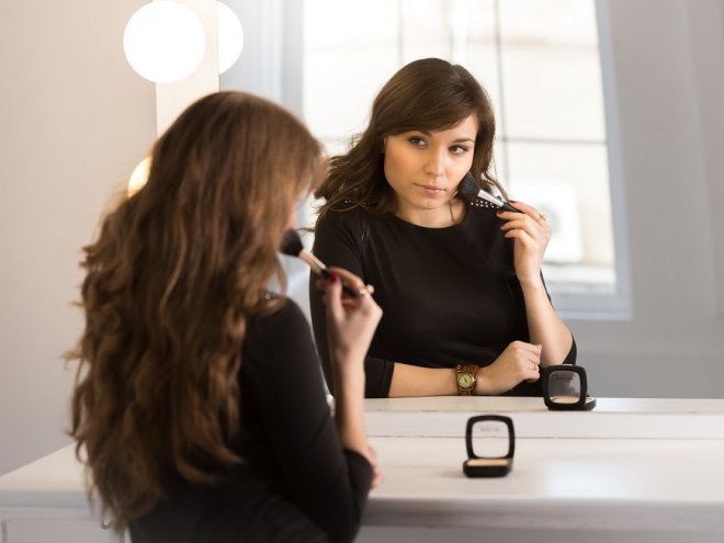 Женщина делает макияж перед зеркалом